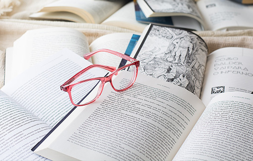 a pile of books with reading glasses