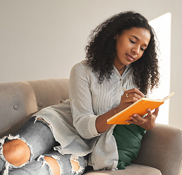 Woman sitting on a sofa writing a list