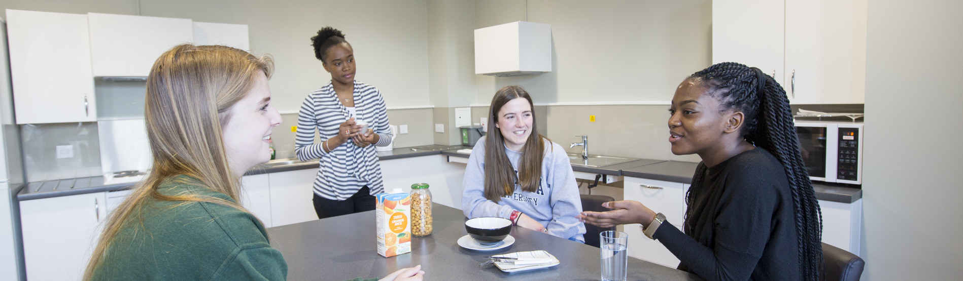 a group of female students chatting in a kitchen