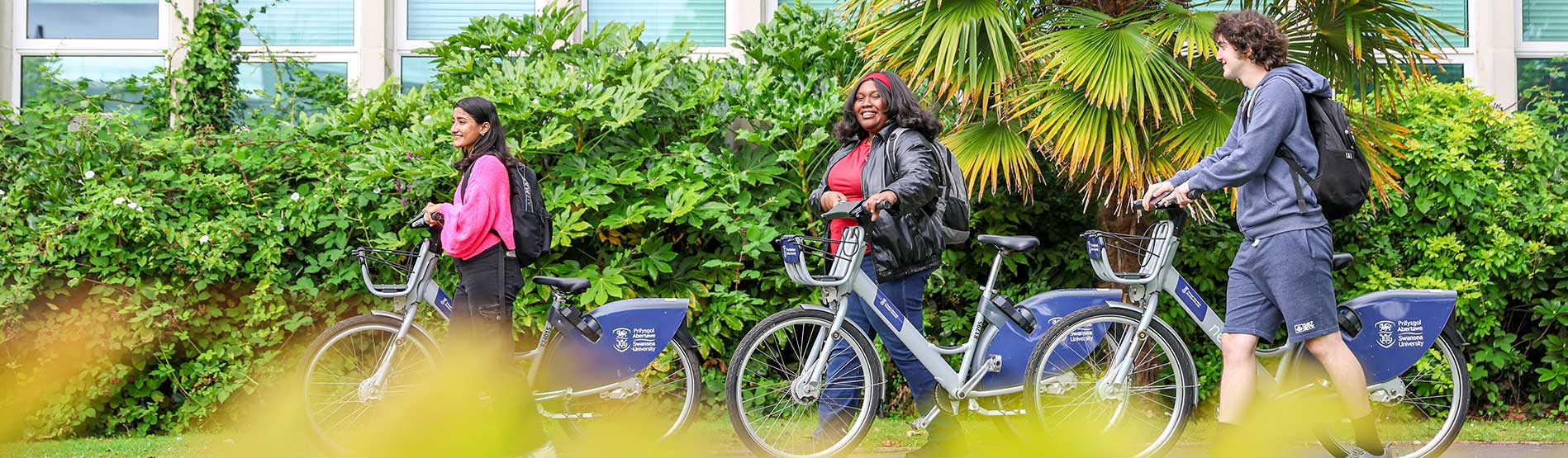 Swanse University students walking with Swansea university Cycles on campus