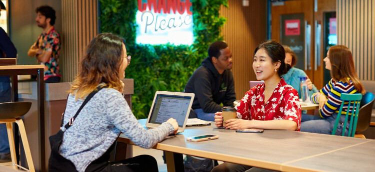 Students chatting in cafe with laptop