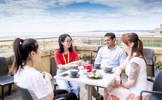 students sat around table on terrace beach background